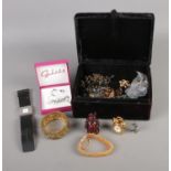 A black velvet jewellery box containing an assortment of costume jewellery such as necklaces,