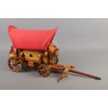 A wooden Romany wagon lamp featuring cloth canopy and decorative metalware detailing.