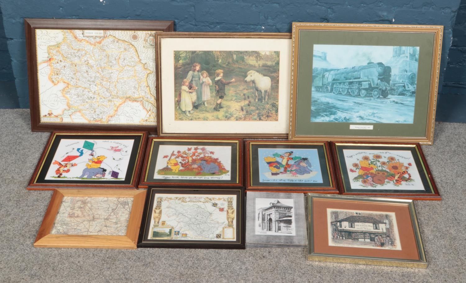 A collection of printed maps, prints and Winnie-the-Pooh cross-stitches.