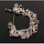 A Silver and white metal charm bracelet. with 33 charms, key, aeroplane, fire engine, top hat,