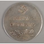 A white metal medallion baring Swastika to one side and eagle to the other. Staatsministerium