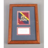 A framed 16th/5th The Queen's Royal Lancers military cap badge.