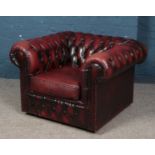A deep buttoned oxblood leather Chesterfield style arm chair. Small tear to back of chair.