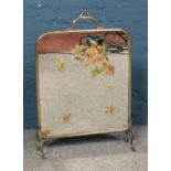 A brass mirrored fire screen featuring painted autumnal leaf decoration.