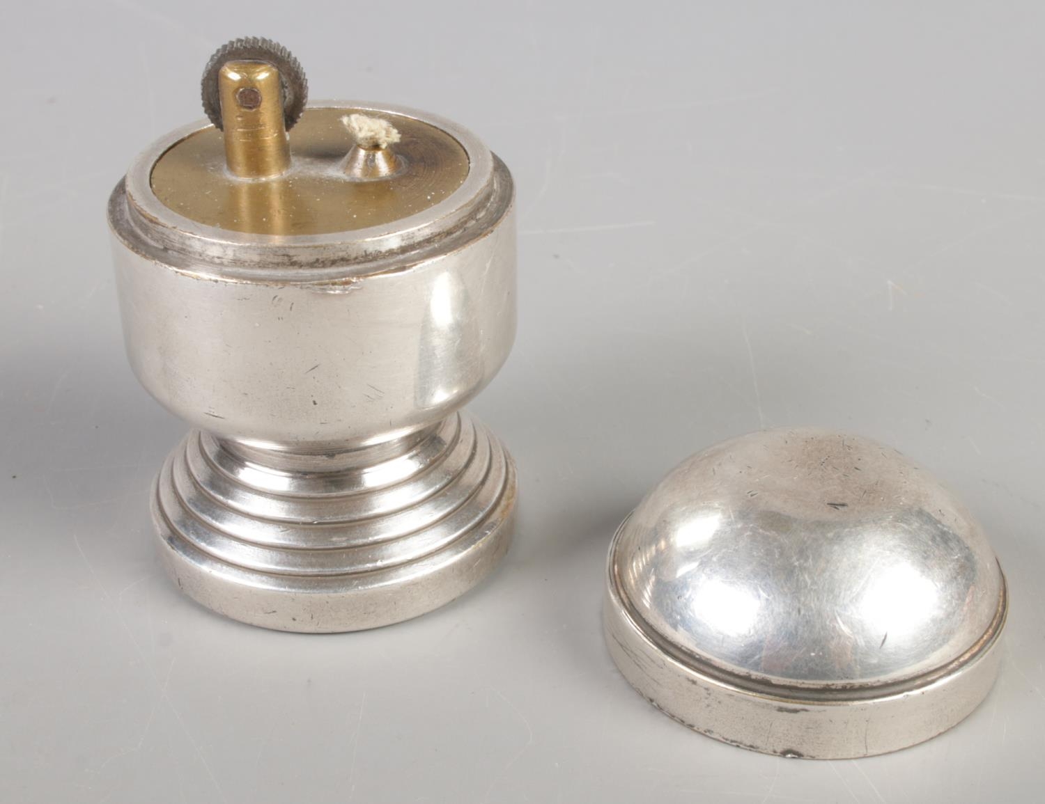 A white metal table lighter raised on circular stepped base. (8cm) - Image 2 of 2