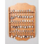 A quantity of collectors spoons displayed on wall mounted rack.