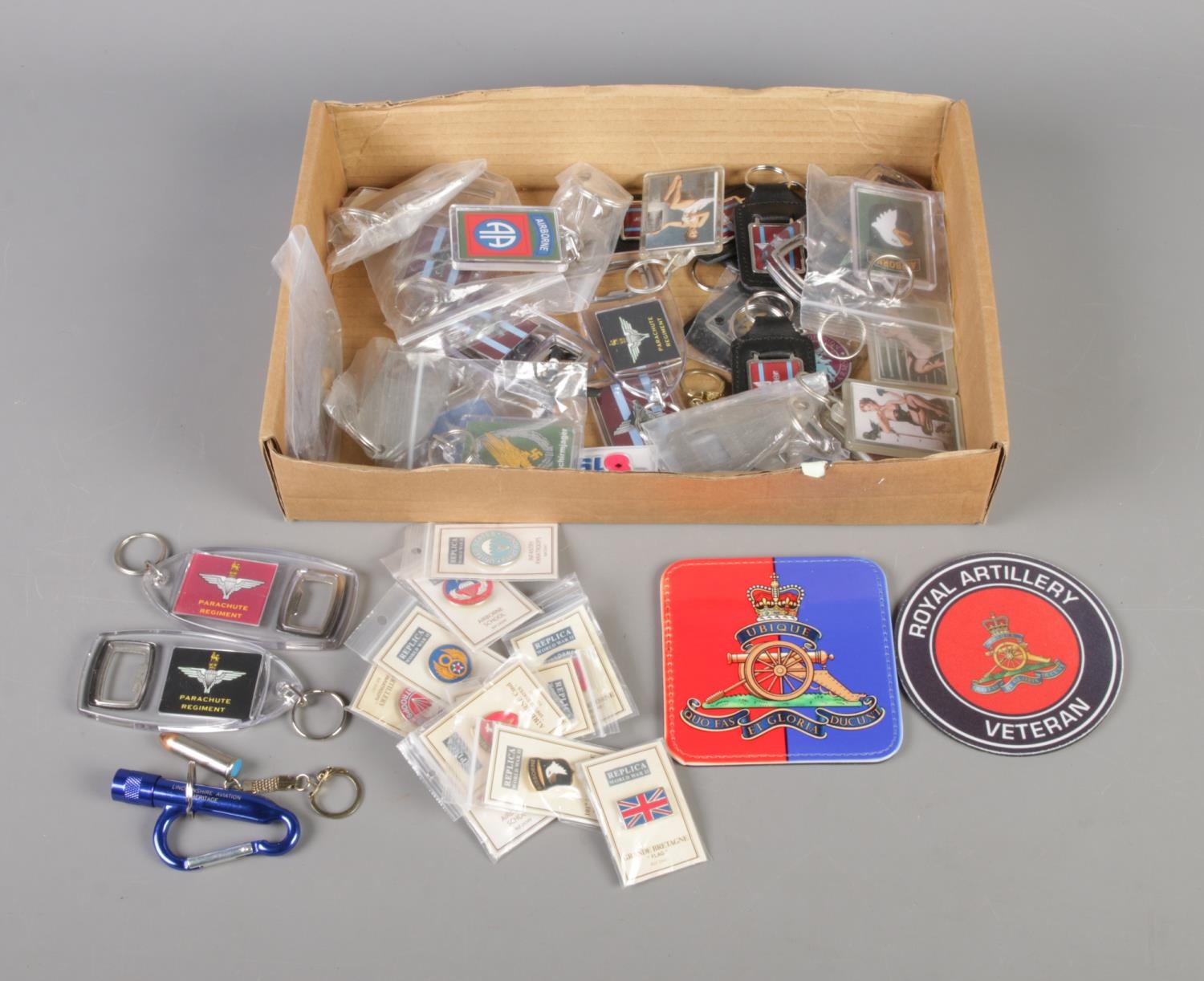 A collection of military themed keyrings and enamel pin badges, including Parachute Regiment and