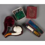 A cased meerschaum pipe with amber coloured mouth piece along with cased cheroot holder and a
