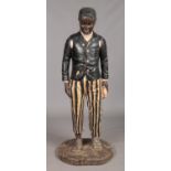 A large carved wooden blackamoor and polychrome statue of a young boy dressed in ragged jacket and