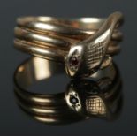 A 9ct coiled snake ring featuring garnet set eyes and cross hatch detail to head. Size R 4.67g.