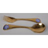 A silver gilt fork and spoon set by Georg Jensen, with matching enamel blue floral decoration to