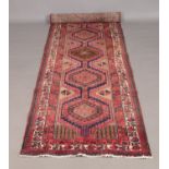 A large red ground thick pile Persian Heriz runner with geometric design. 310cm x 106cm