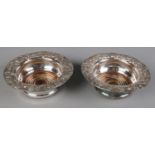 A pair of ornate silver plate wine bottle coasters. Decorated with vines and fruit.