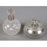 A cut glass jar with silver lid and rim along with a cut glass silver collared scent bottle.