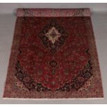 A washed red ground fine woven Persian Kashan carpet with floral medallion design. 335cm x 200cm.