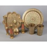 A collection of engraved Indian brass ware including tumblers and charger.