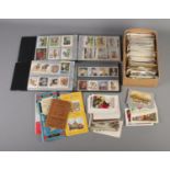 A large quantity of vintage postcards along with two albums of cigarette cards.