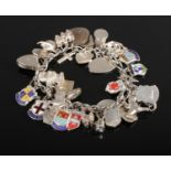 A silver and white metal charm bracelet containing a large quantity of charms, including US dime,