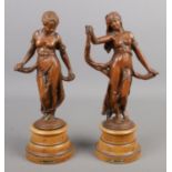 A pair of cast metal figures raised on wooden plinths, titled Modistie and Gaiete. 30cm.