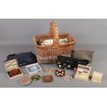 A wicker basket containing an assortment of ladies accessories. To include purses, Stratton powder