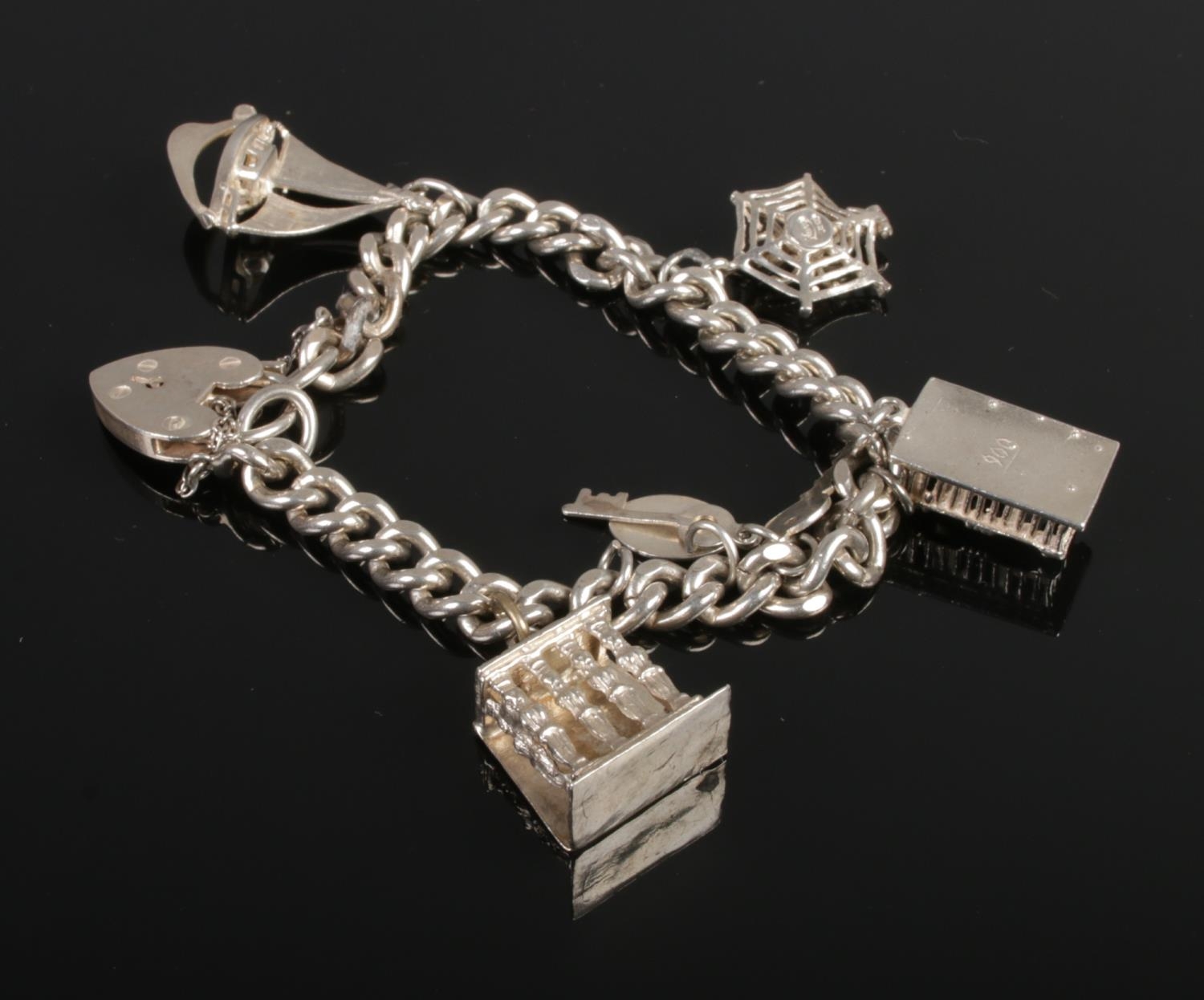 A silver and white metal charm bracelet, on hallmarked silver chain. Contains six charms including