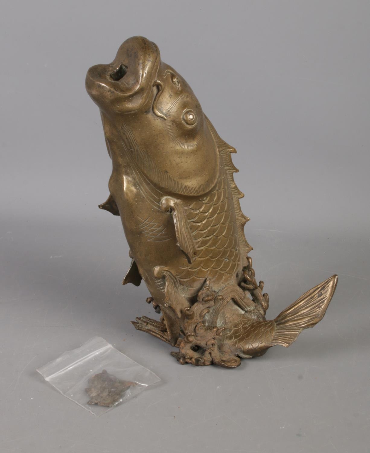 A bronze figure of a leaping carp. Portion of tail is missing with some damage to body and water