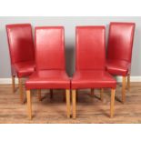 Four red faux leather dining chairs.