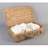 A wicker basket containing an assortment of linen, mainly doilies.