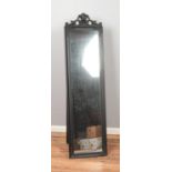 A modern black floor standing mirror featuring carved detail.