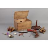 A wooden box of collectables. Includes pair of desk cannons, corkscrews, compass, razors and