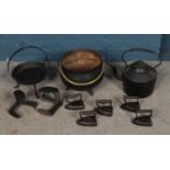 A collection of metal wares to include cast iron pan, irons and cauldron.