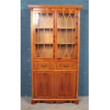 A yew wood bookcase, with astragal glazed front, reeded columns and carved corner sections.