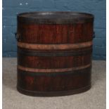 A stained storage oak barrel featuring twin handles and removable lid. Approx. 54cm tall. Bands have