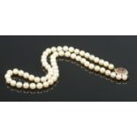 A cultured pearl necklace, with 9ct Gold clasp and central amethyst coloured stone.