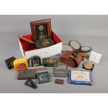 A box of collectables. Includes glass casket, barge ware, framed military badges, alarm clocks etc.