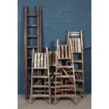 Five sets of vintage wooden stepladders.