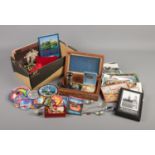 A box of collectables. Includes postcards, sew on badges of various destinations, gold plated