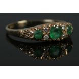 A 9ct Gold, emerald and diamond spacer ring. Size SÂ½. Total weight: 2.3g. Some small chips to