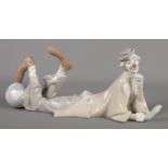 A Lladro ceramic reclining clown, with ball at his feet. Length: 36cm. Repair to foot touching the
