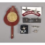 A collection of military cap badges, pins and horse brass including several Parachute Regiment