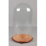 A Victorian glass dome on wooden stand. Height of dome 41cm, Diameter of base 23cm.