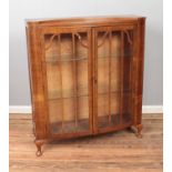 A walnut and glass display cabinet featuring two glass shelves and double doors. Approx.