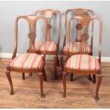 Four hardwood chairs with upholstered seats and carved back detail.