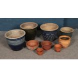 A collection of terracotta planters of various sizes including blue glazed examples.