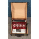 A cased Amigo accordion with red marbled effect body.