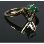 A modern emerald ring, set into a chevron of channel set small diamond. Tests to 14ct Gold. Size