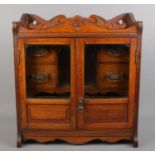 An oak smokers cabinet with carved pediment and beveled glass doors. 46cm high.
