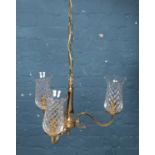 A three branch brass chandelier, with glass shades.