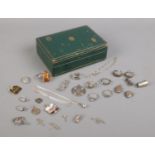 A small green box containing various oddments of silver jewellery. To include charms, rings,
