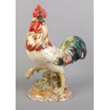 An Italian ceramic cockerel with gilt detailing to the base. 29cm high. Paint peeling to some